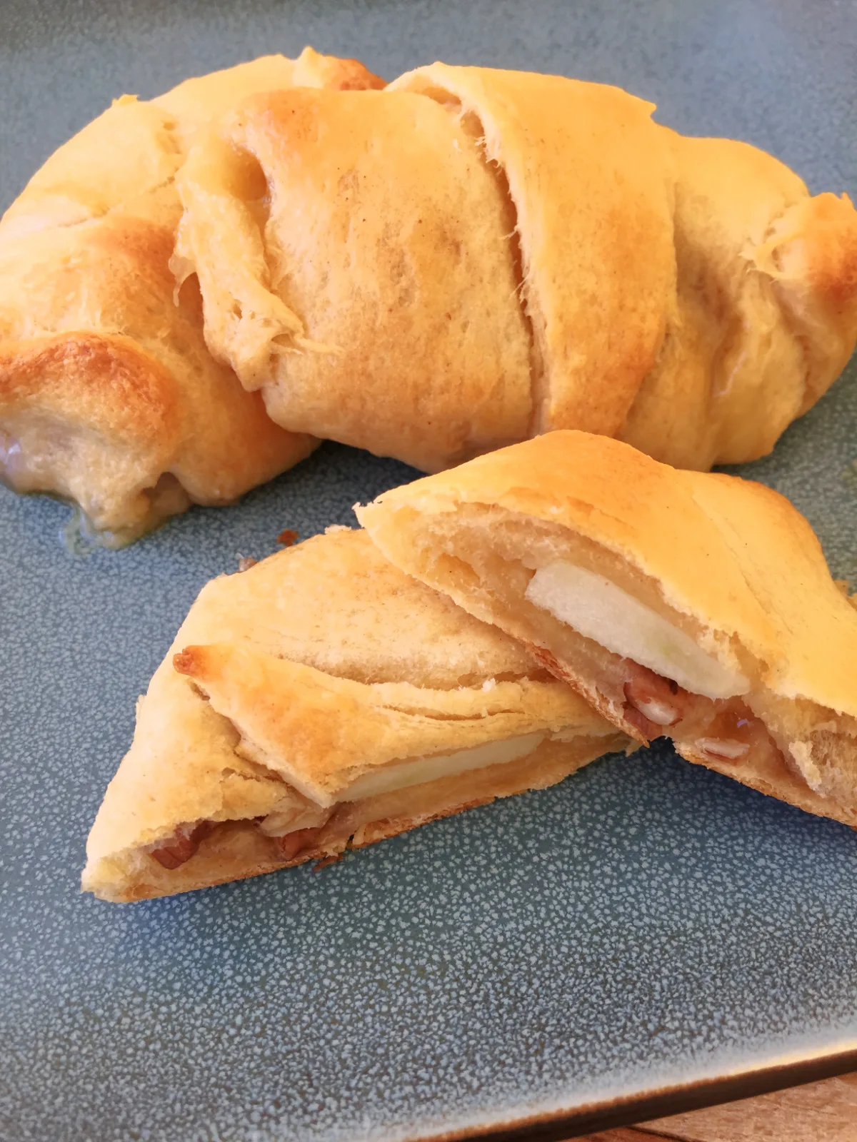 Apple Brie Roll Ups on a blue plate with one cut in half.
