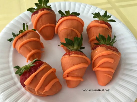 Strawberries made to look like carrots on a white plate.