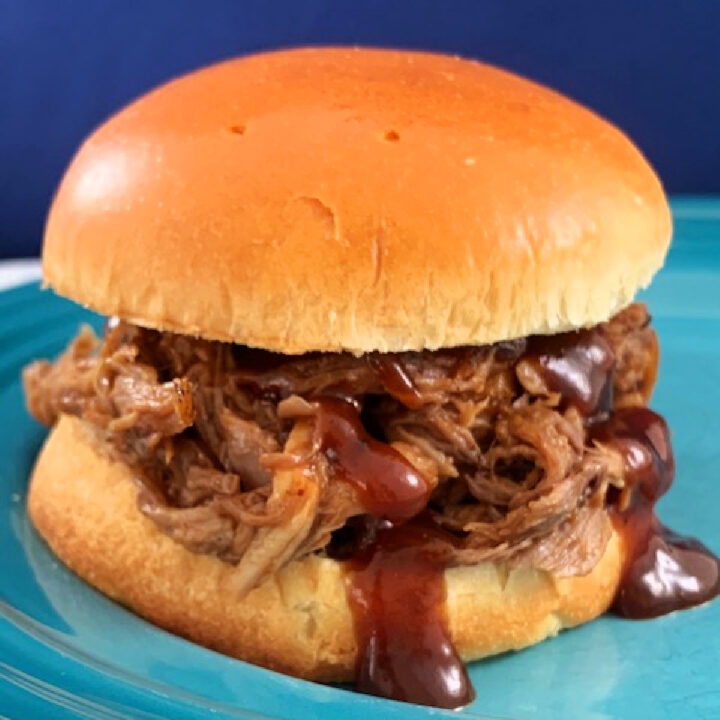 Pulled pork sandwich with barbecue sauce dripping off the bun.