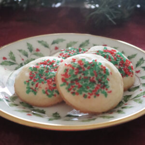 Four butter cookies with colored sugar on a Christmas plate.