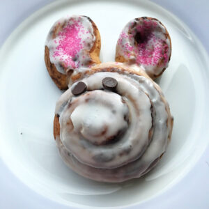 A cinnamon roll in the shape of a bunny on a pastel plate.