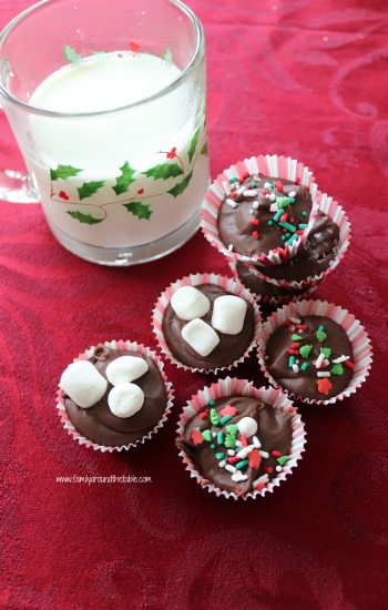Hazelnut hot chocolate drops on a red tablecloth next to a mug of milk.