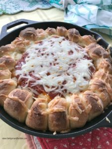 A pizza dip surrounded by bread in a cast iron skillet.