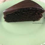 A slice of double chocolate fudge cake on a green plate.