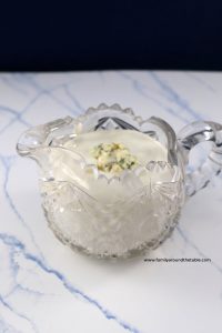 A small pitcher of blue cheese dressing on a marble countertop.