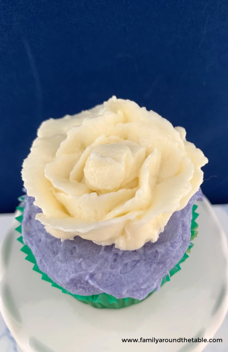 White chocolate buttercream rose on lavender frosting on a cupcake.