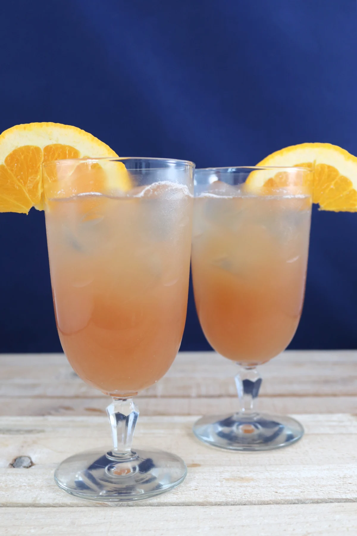 Two glasses of non-alcoholic cranberry orange spritzer garnished with an orange slice.