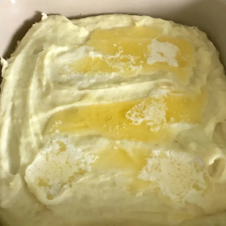 Overhead photo of mashed potatoes in a serving dish with butter.