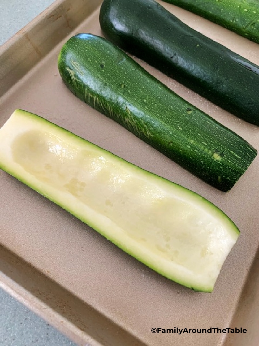 Zucchini halves on a baking sheet. One right side up, 3 cut side down.