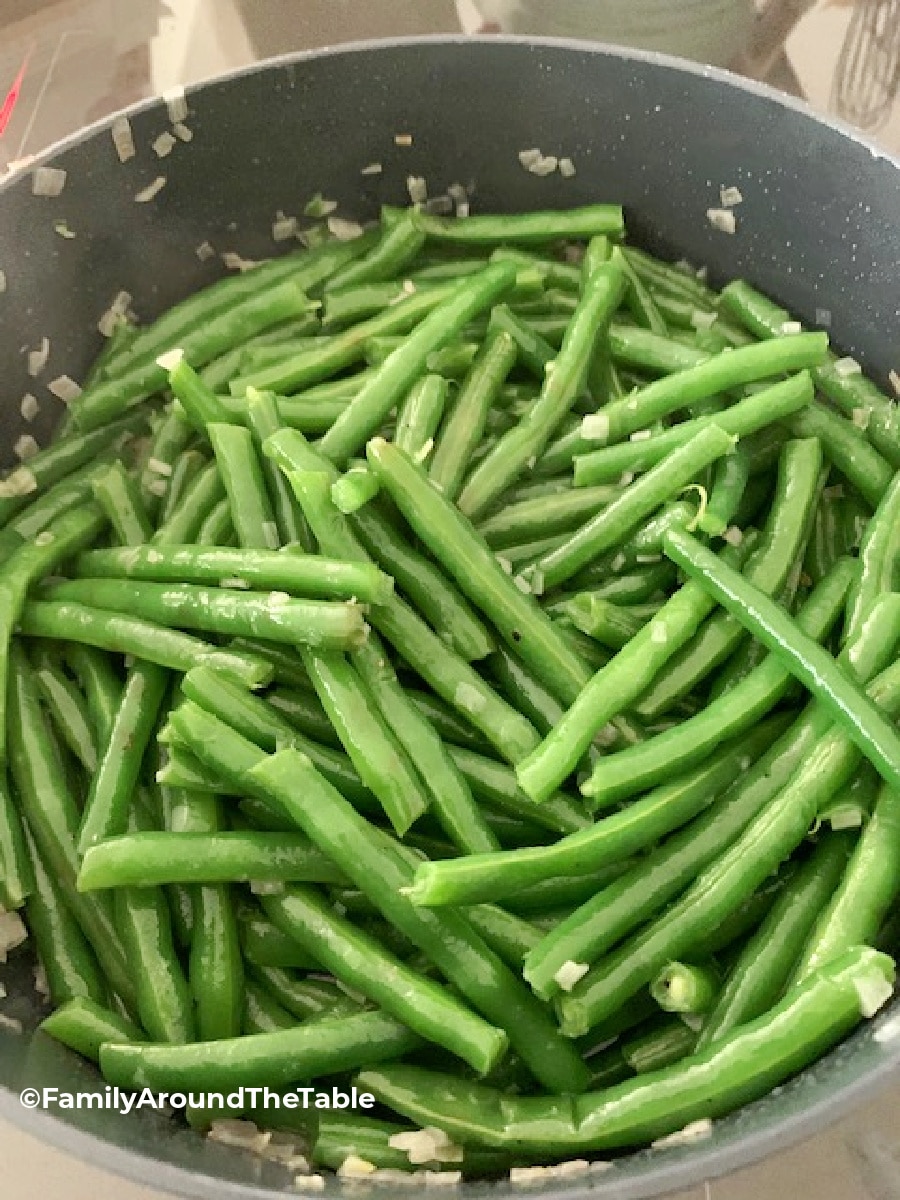 Overhead photo of string beans with shallots in a pan.