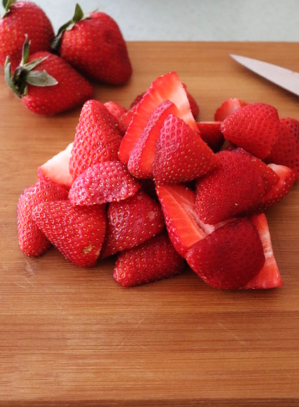 Cut strawberries on a cutting board.