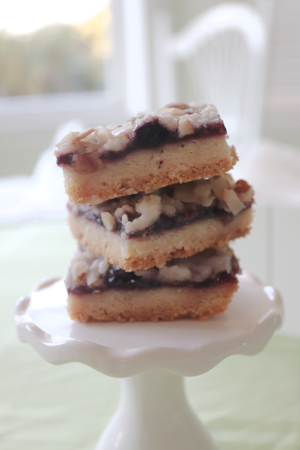 Side view of three blueberry lemon bars stacked on a mini cake stand.