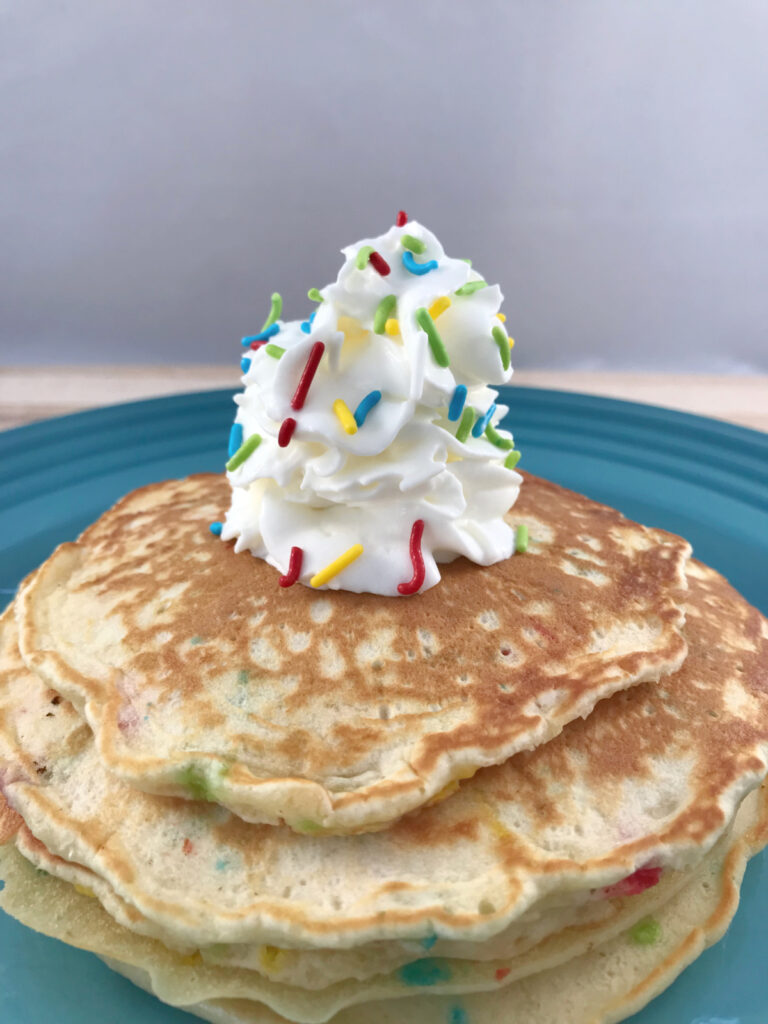 Funfetti pancakes topped with whipped cream and sprinkles.