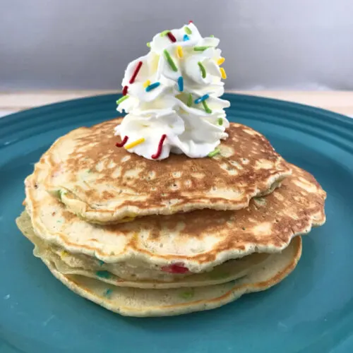 Funfetti pancakes topped with whipped cream and sprinkles.