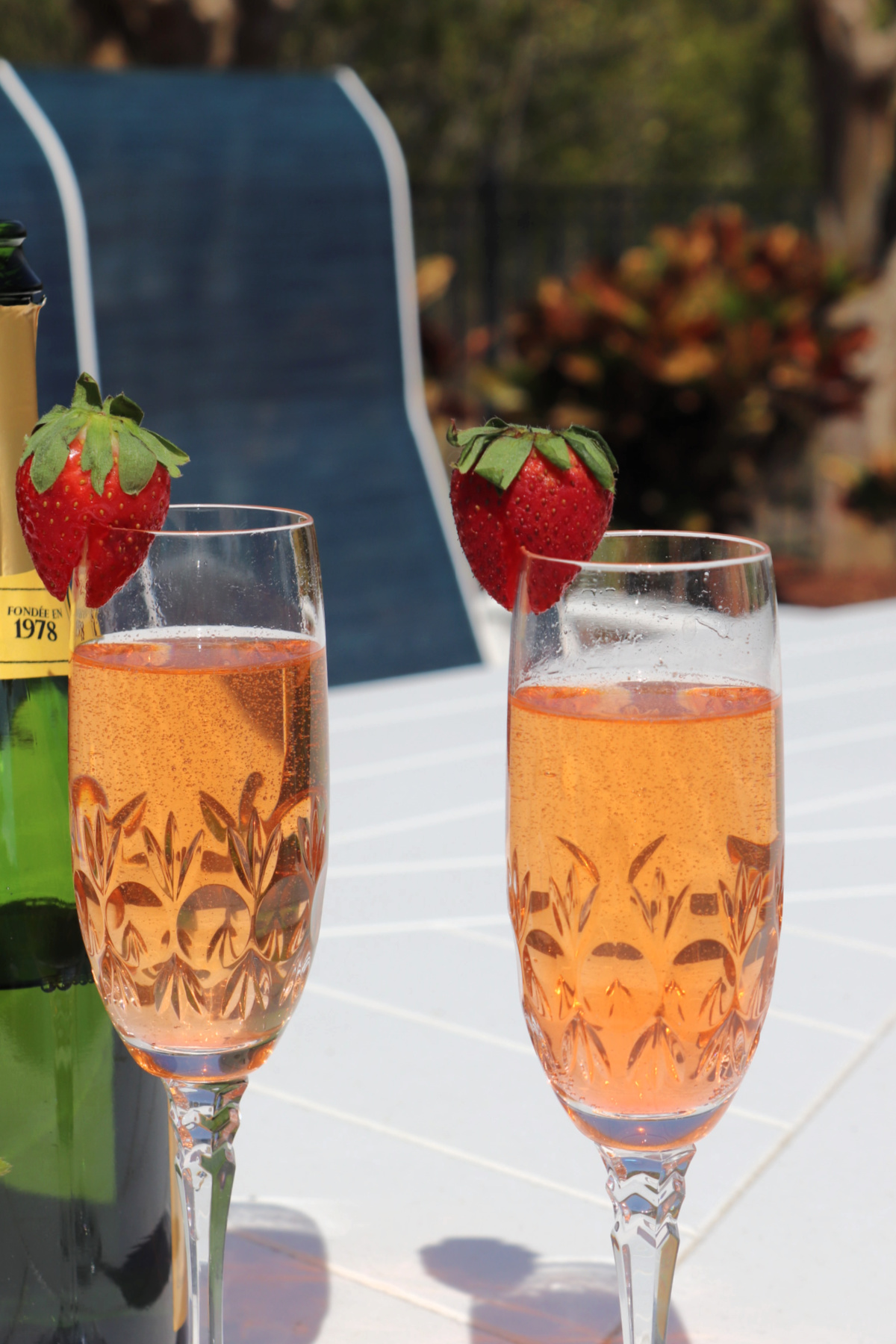 Strawberry bellini recipe in two champagne flutes garnished with a whole strawberry.