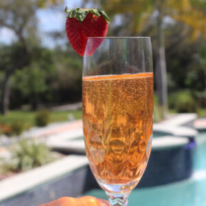 Strawberry bellini in a champagne flute with a strawberry garnish.