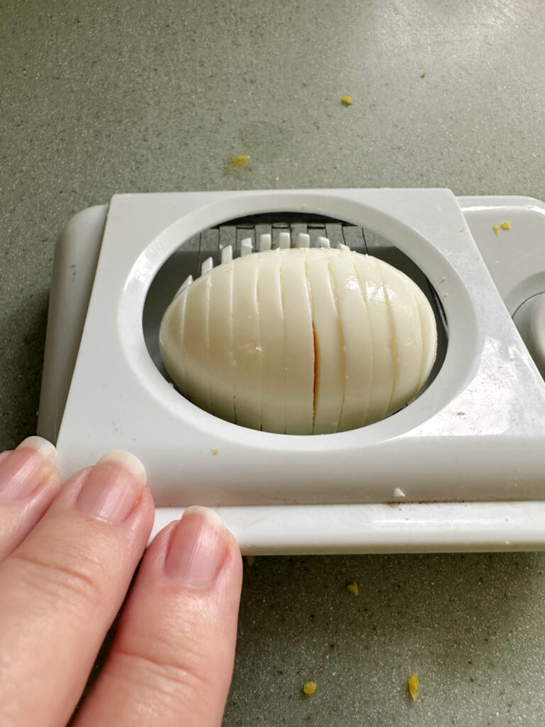 An egg being sliced in an egg slicer.