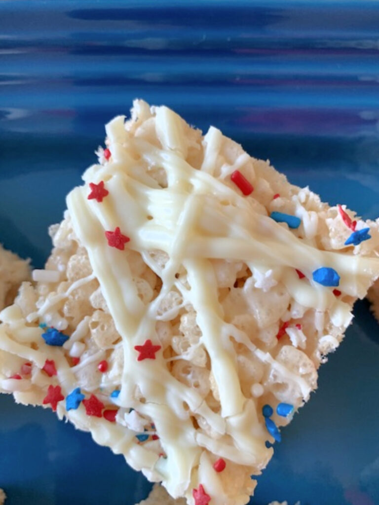 Overhead view of a rice krispie treat drizzled with white chocolate and patriotic sprinkles.