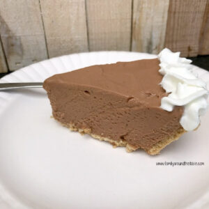 A slice of chocolate pie garnished with whipped cream on a on a white plate.