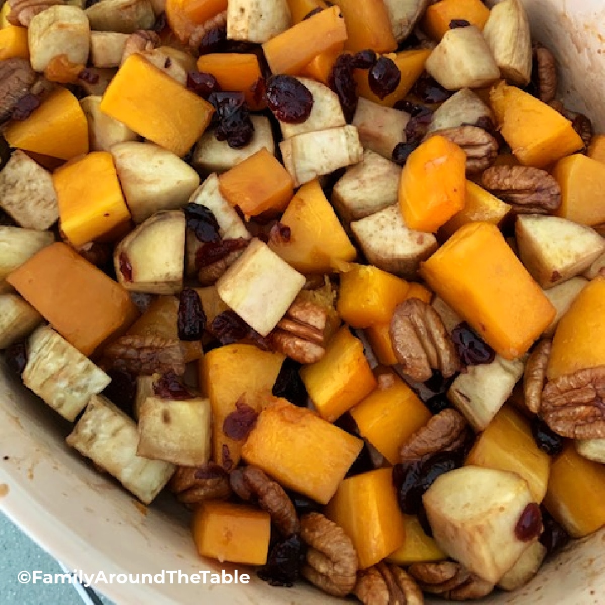 A fall vegetable medley in a baking dish with pecans.