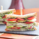 Tomato and cucumber sandwich on a board.