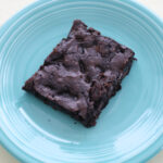 A slice of brownie on a blue plate.