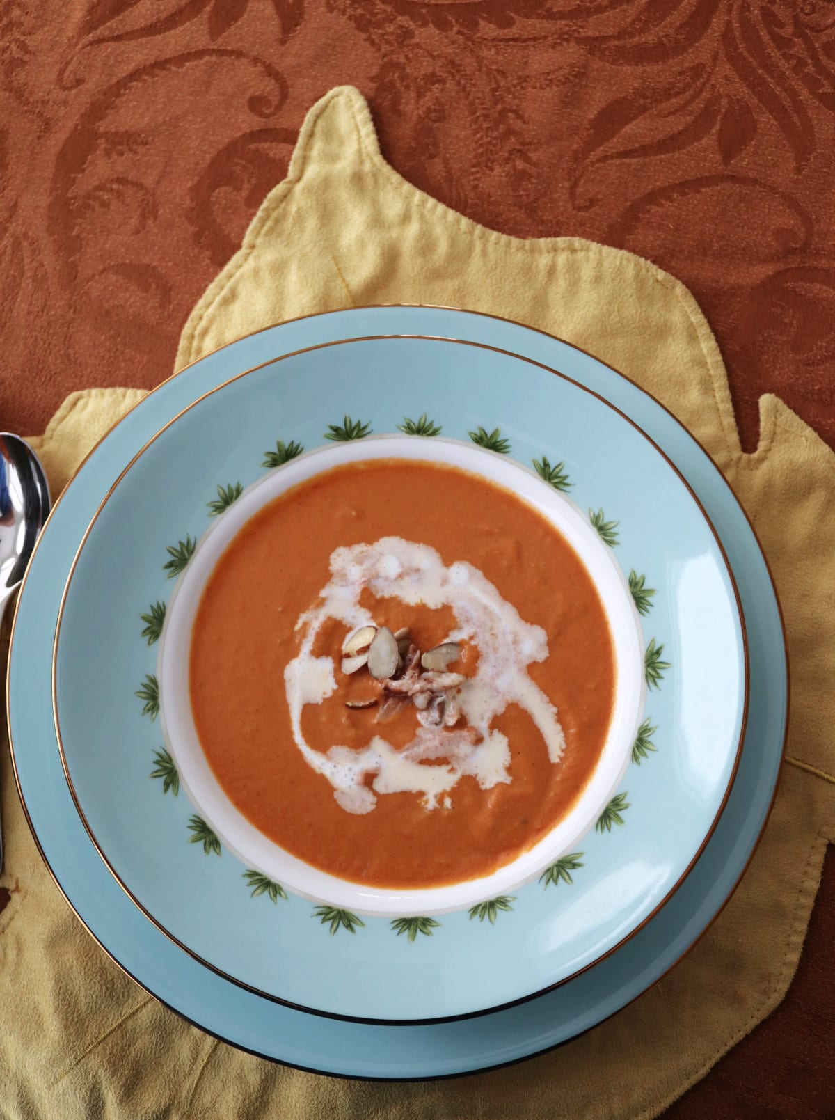 Overhead view of a tomato based bisque in a bowl on a table.