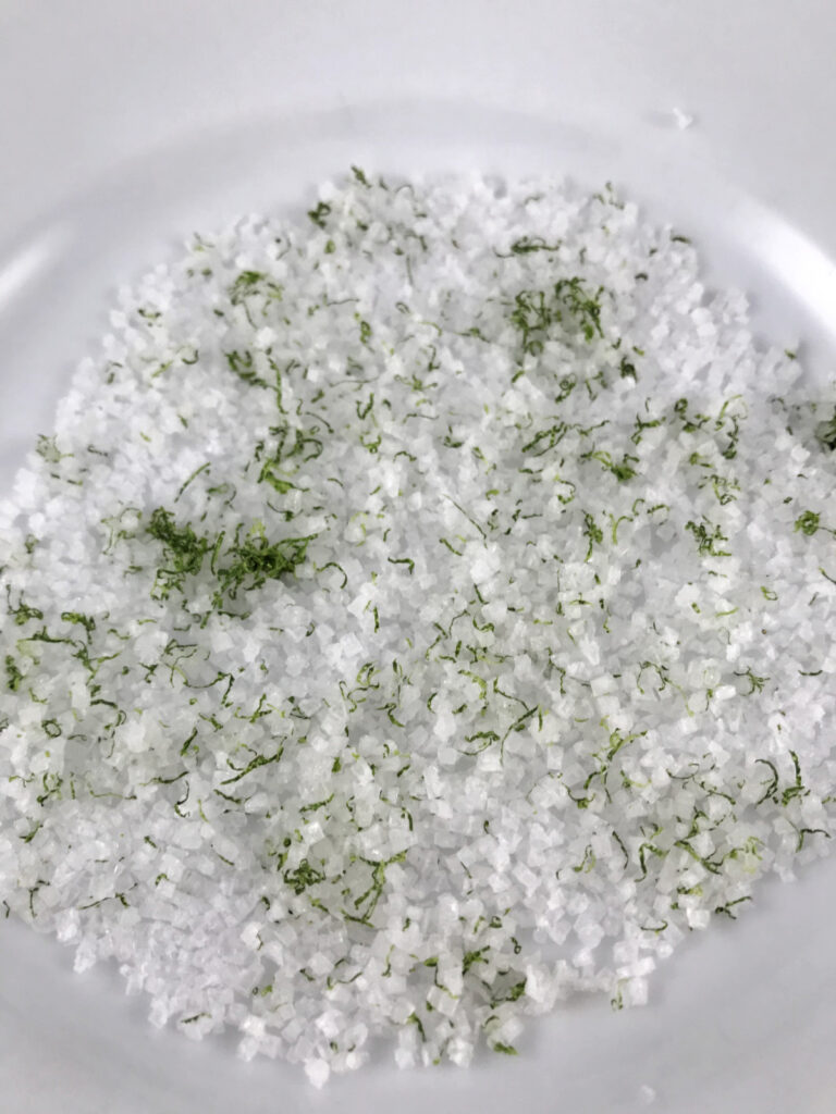 Coarse salt and lime zest on a white plate.