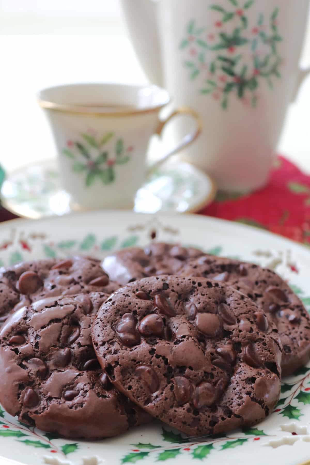 A few chocolate chews on a Christmas plate with a Christmas coffee cup and coffee pot in the background.