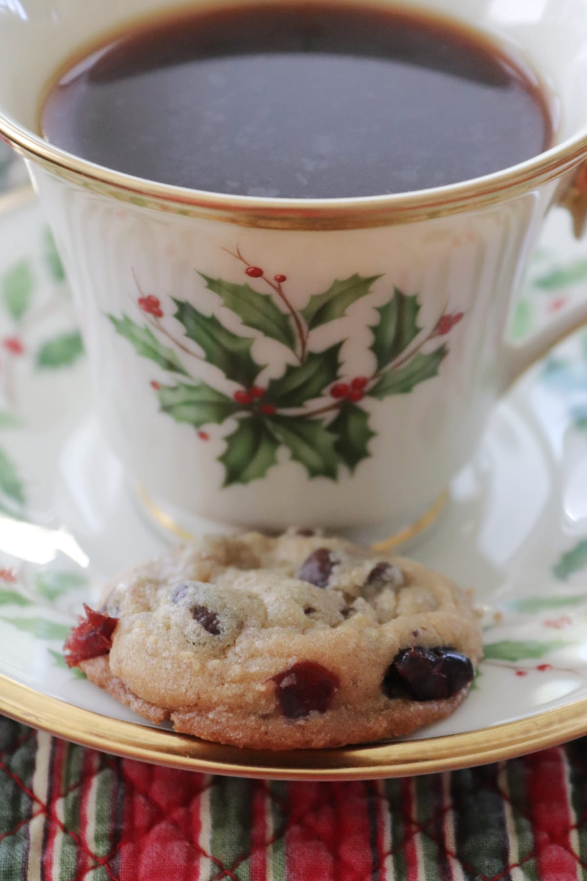 Chocolate Chip Cranberry Cookie on a saucer next to a Christmas cup with coffee in it.