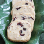 Cranberry orange shortbread cookies on a holly plate as a Pinterest Image.