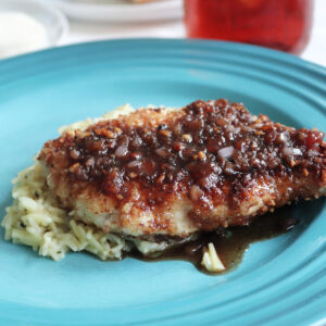 Fried almond chicken with strawberry balsamic sauce on a blue plate.