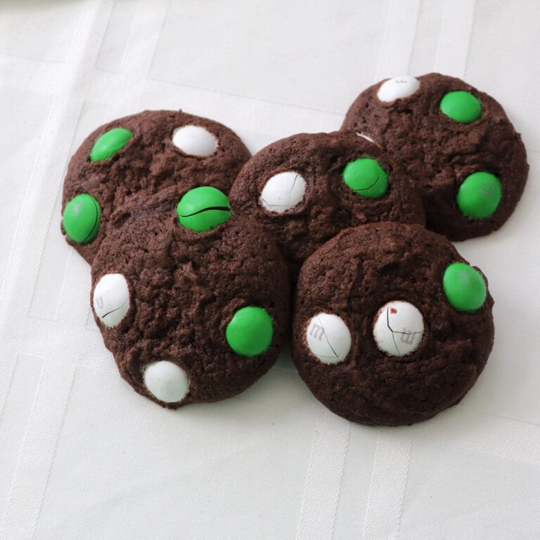 Chocolate mint M&M cookies on a white tablecloth.