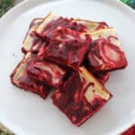 Ovrhead view of red velvet cheesecake bars on a white plate.