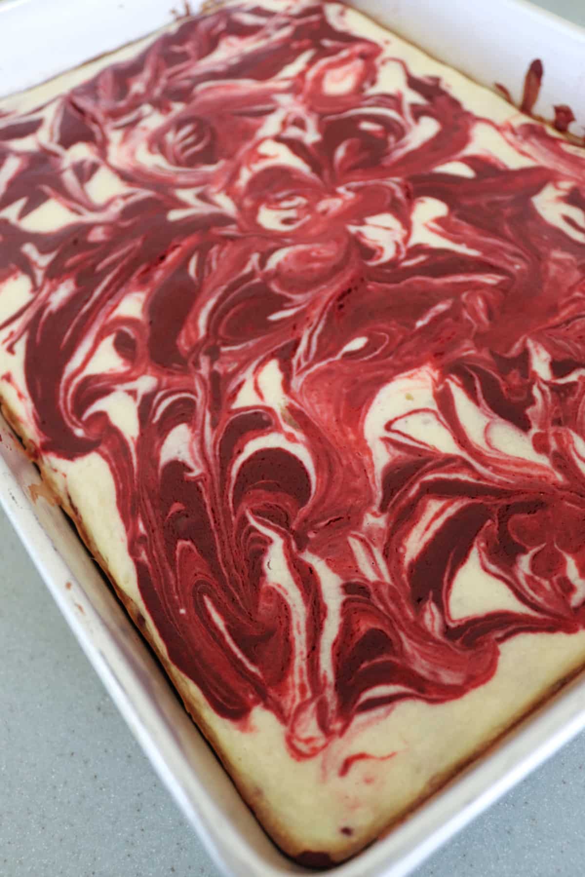 Red velvet cheesecake bars in a rectangle pan.