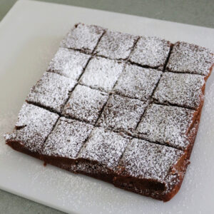 Gingerbread bars on a cutting board that have a powdered sugar dusting.