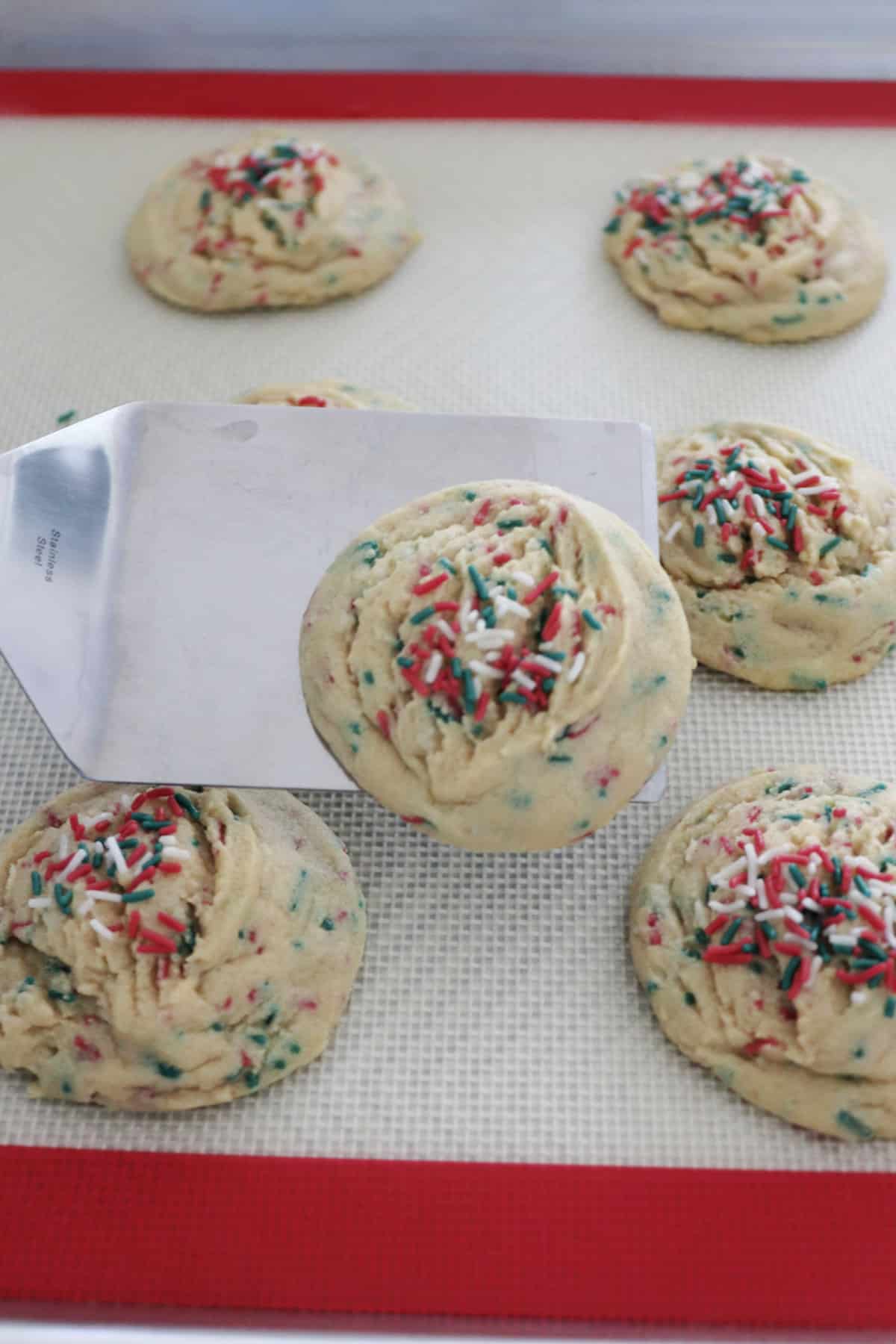 A vanilla pudding cookie on a spatula over a baking sheet with other cookies.