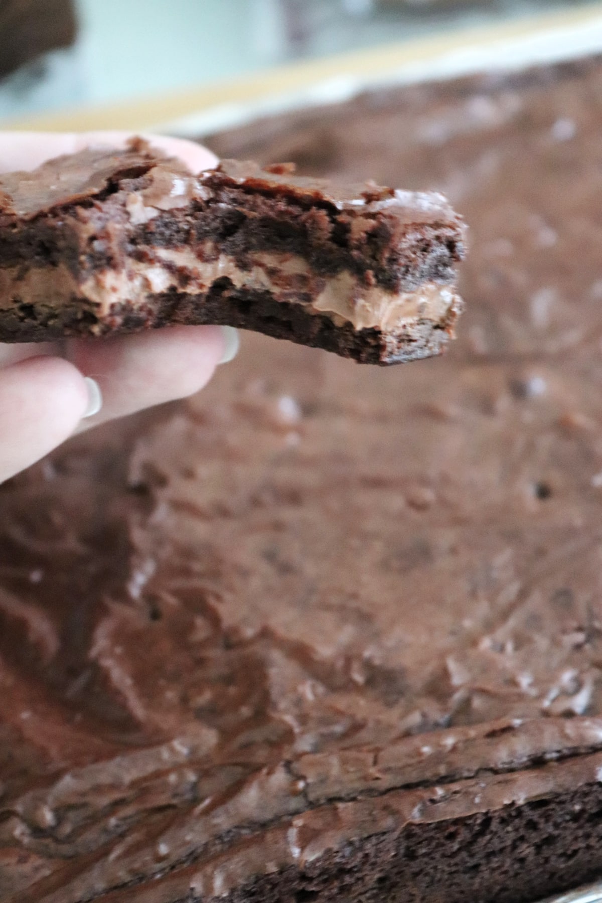 Candy bar brownie being held with a bite taken out of it.