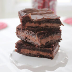 Candy bar brownies stacked on a white stand.
