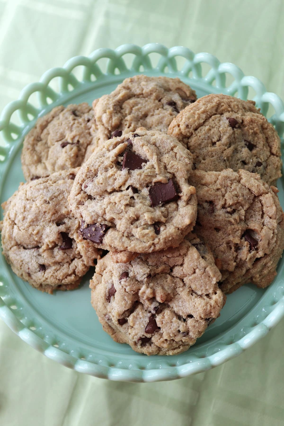 Overhead view of chocolate chip cookies on a green plate.