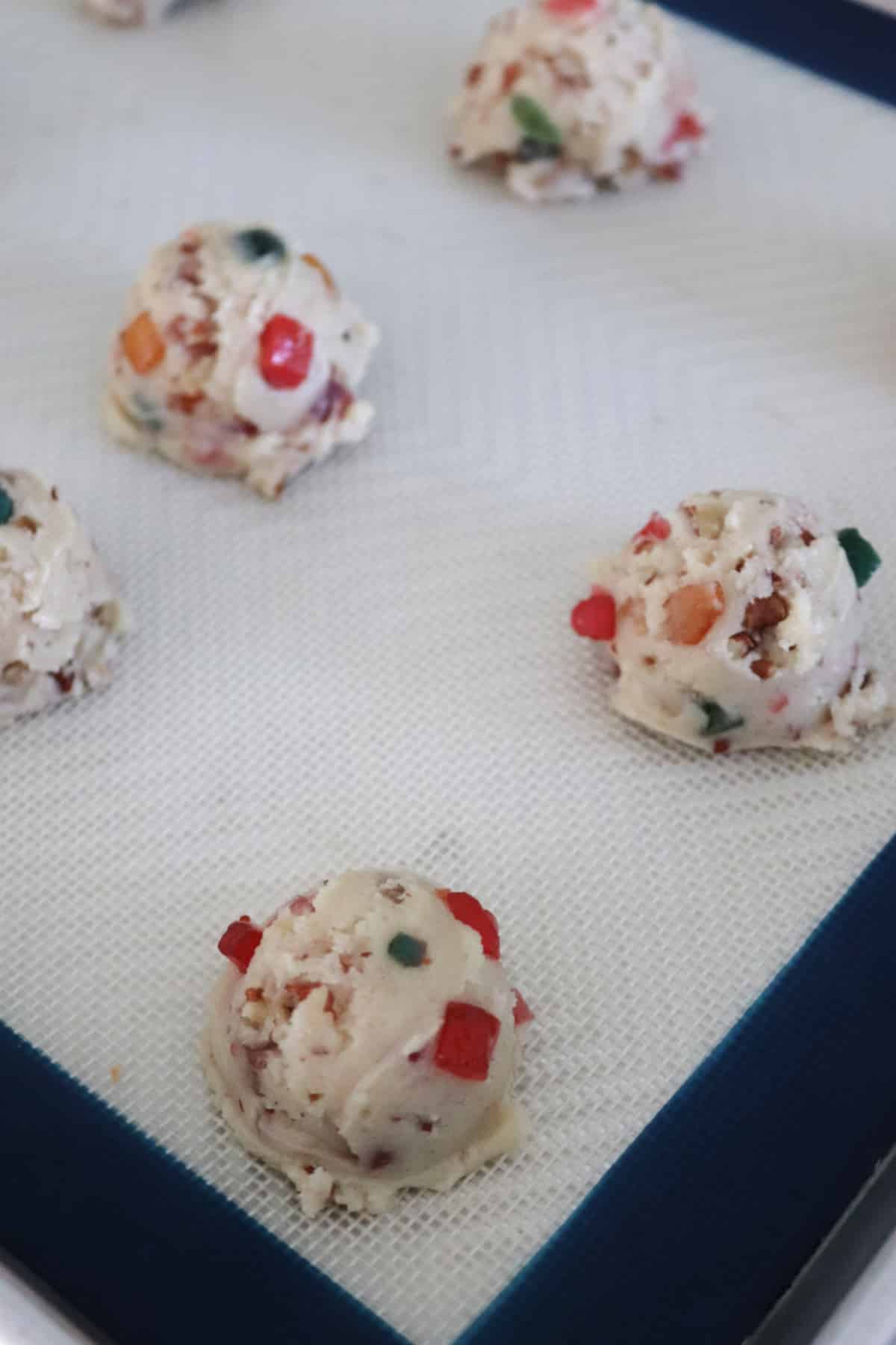 Fruitcake cookie dough balls on a baking sheet.