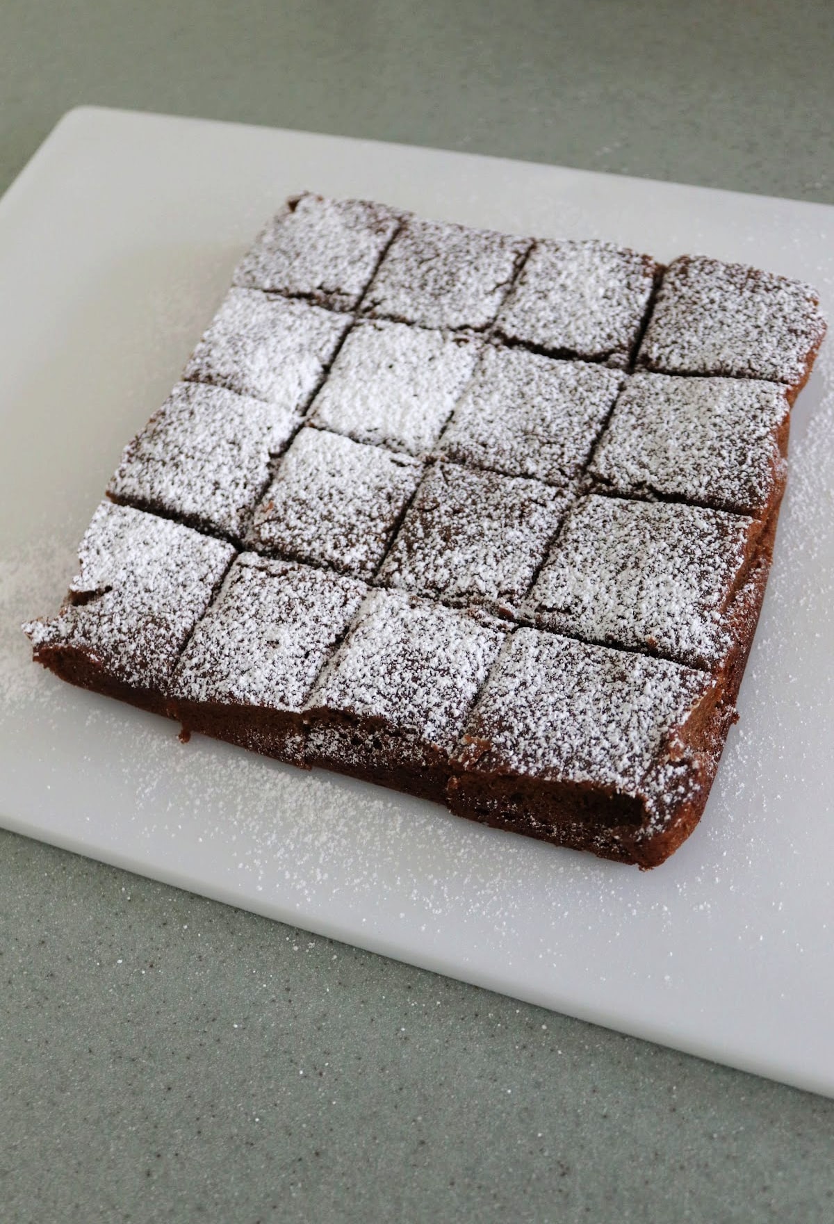 Powdered sugar dusted gingerbread cookie bars on a cutting board.