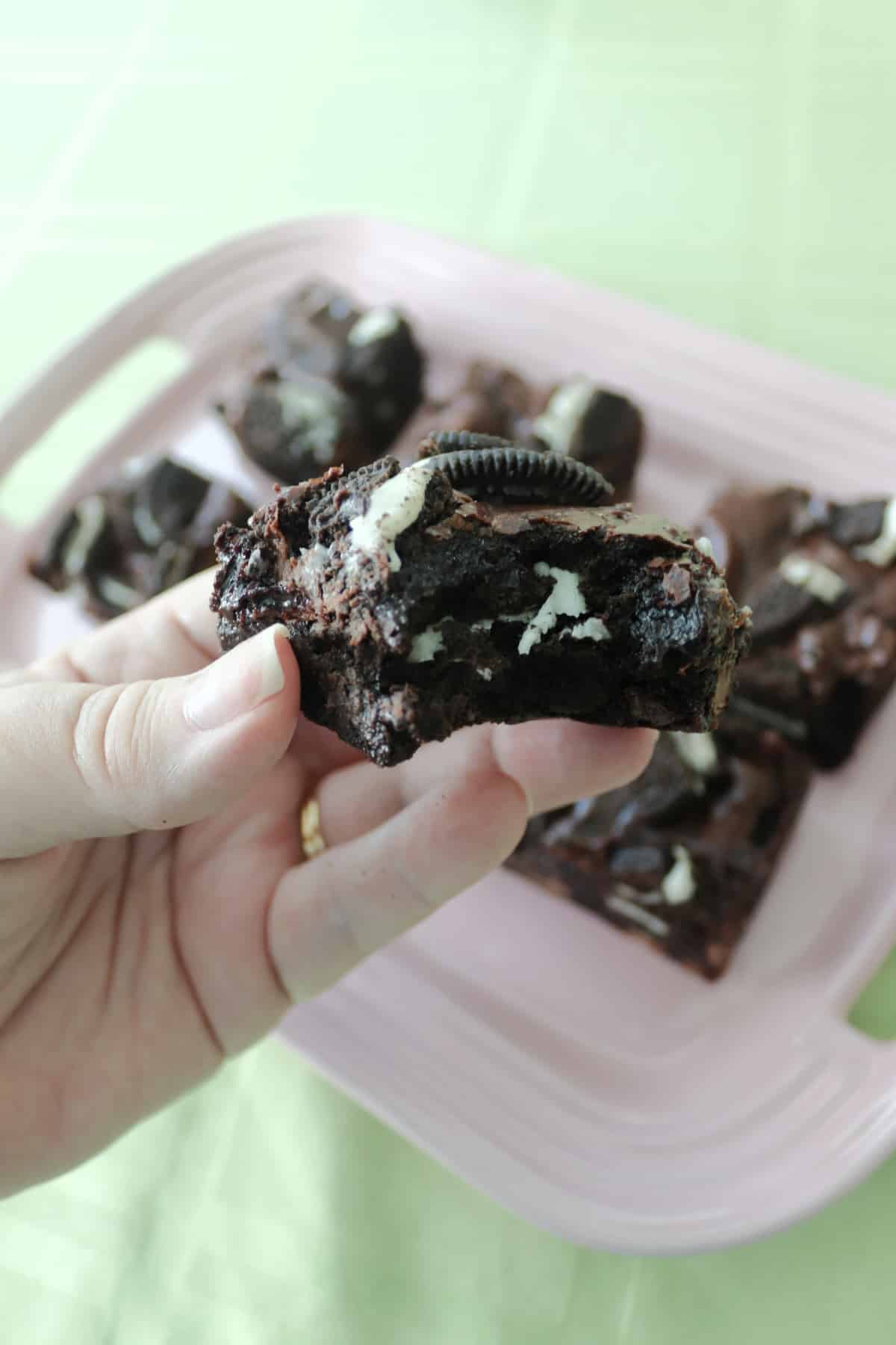 An Oreo brownie being held with a bite taken out of it.