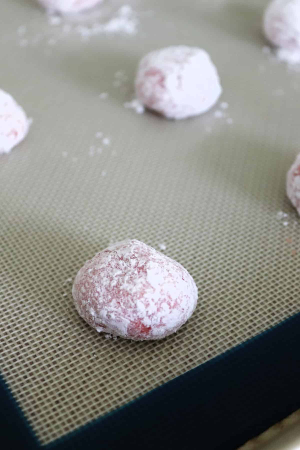Strawberry crinkle cookies on a baking sheet.