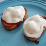 Two open faced meatball sandwiches on a blue plate.