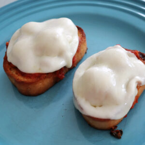 Two open faced meatball sandwiches on a blue plate.