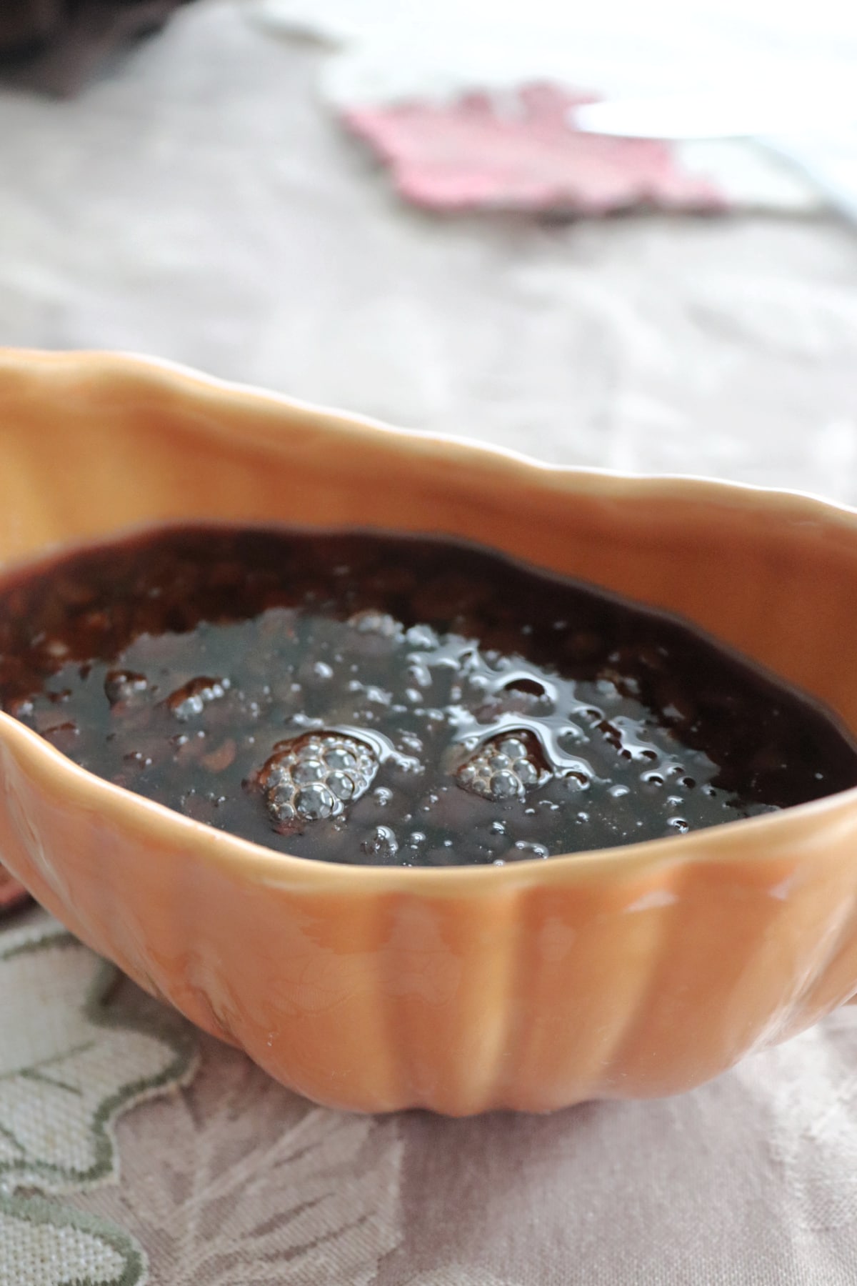 A pumpkin shaped gravy boat with raisin sauce in it.