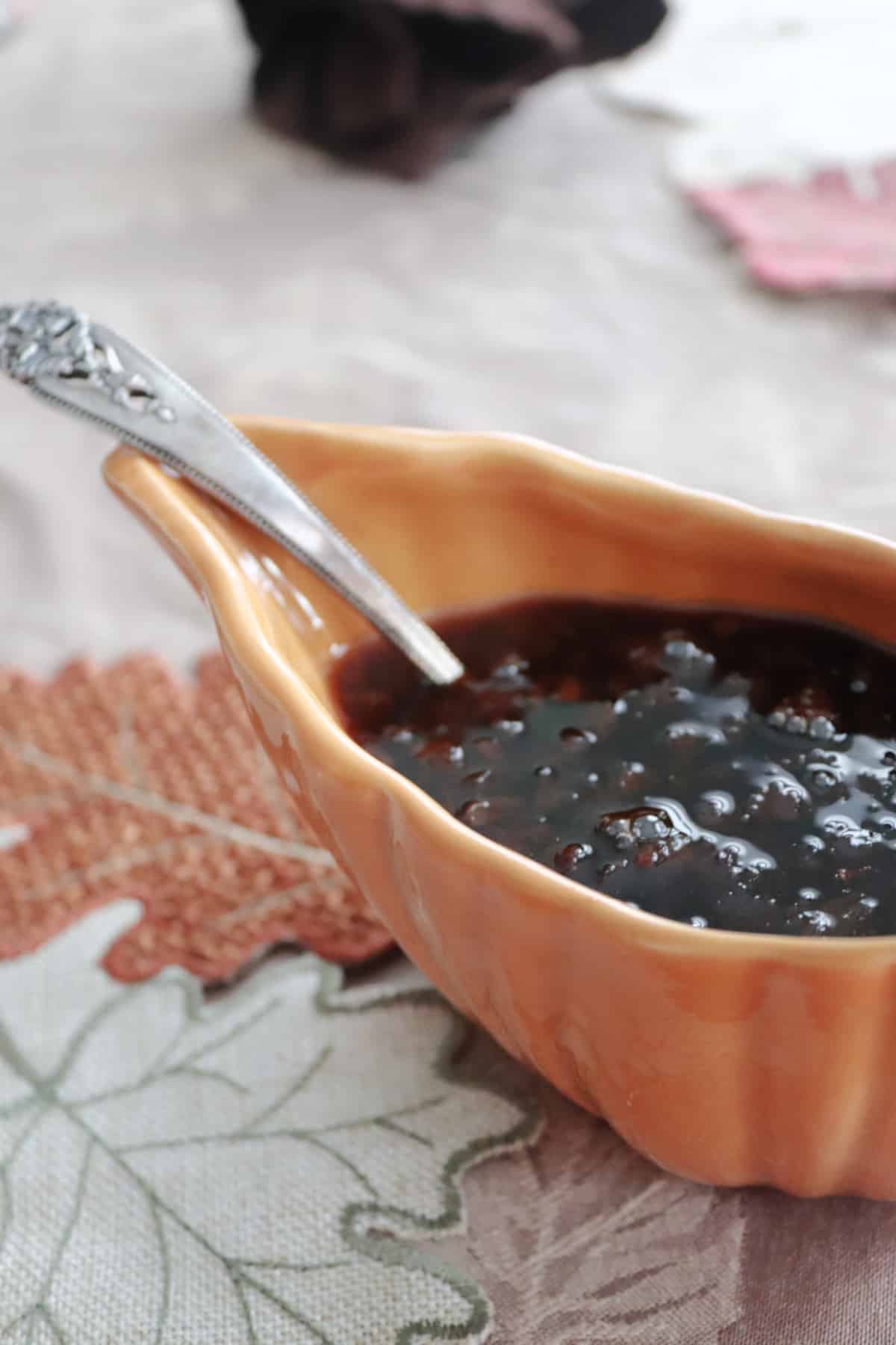 Raisin sauce with a ladle in a gravy boat.