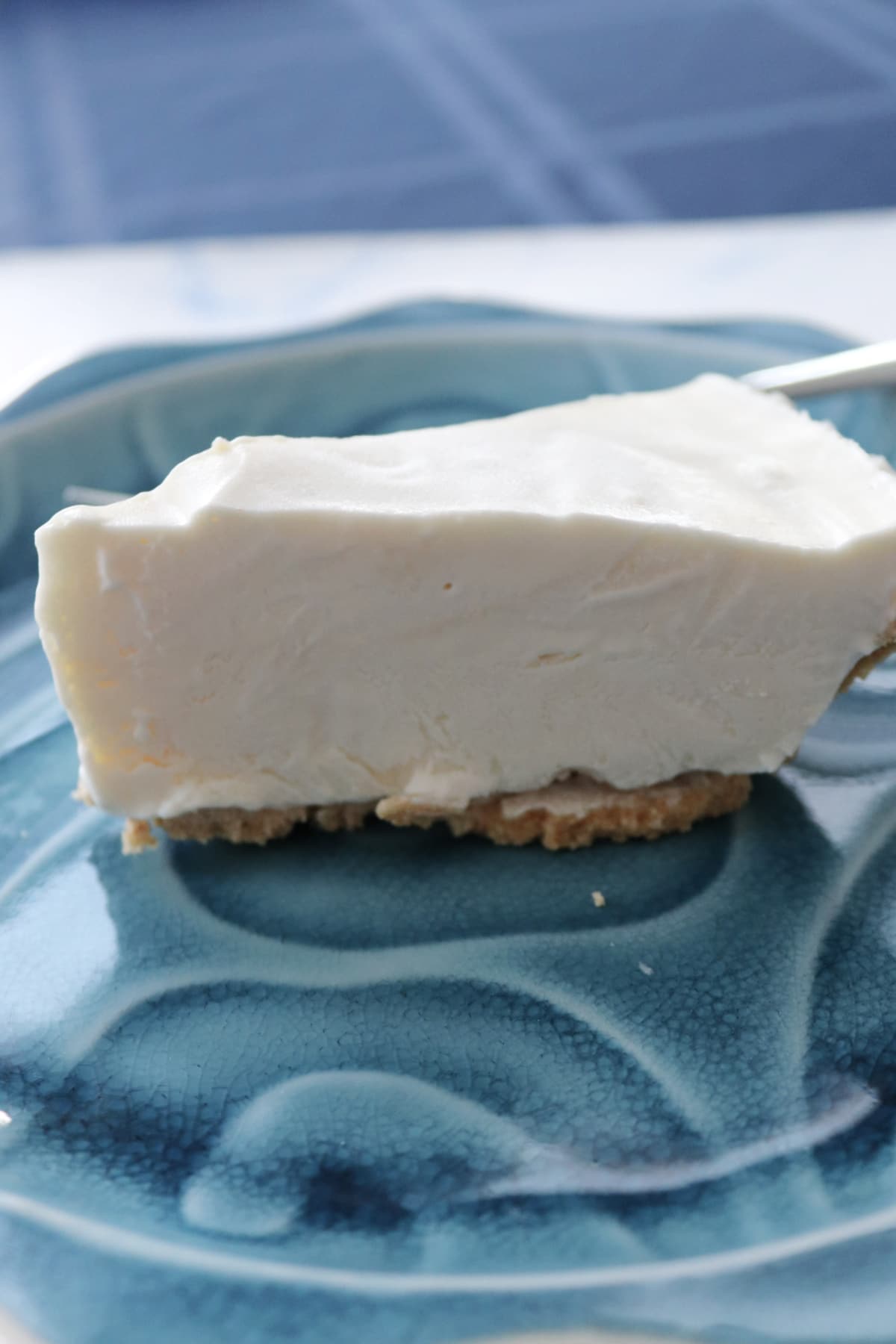 A slice of whipped Key lime pie on a blue plate.