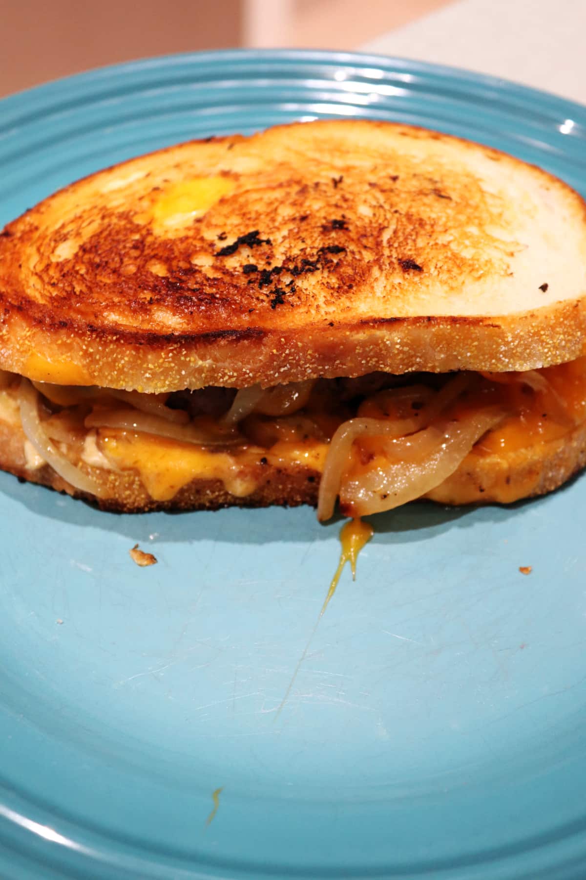 A whole, uncut patty melt on a blue plate.